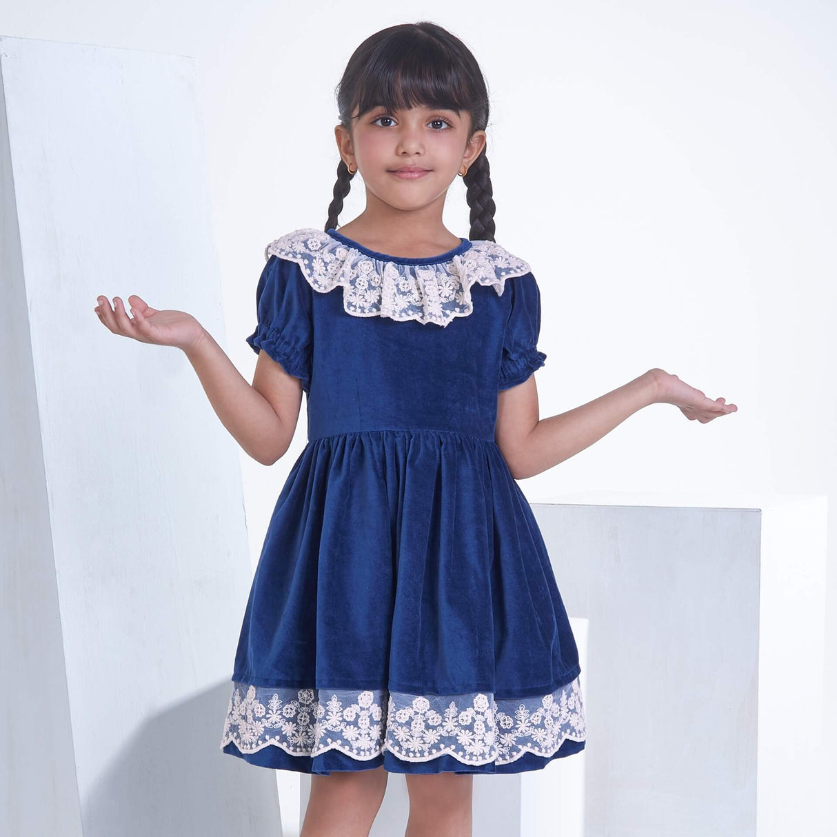 A girl posing in navy velvet dress adorned with white lace