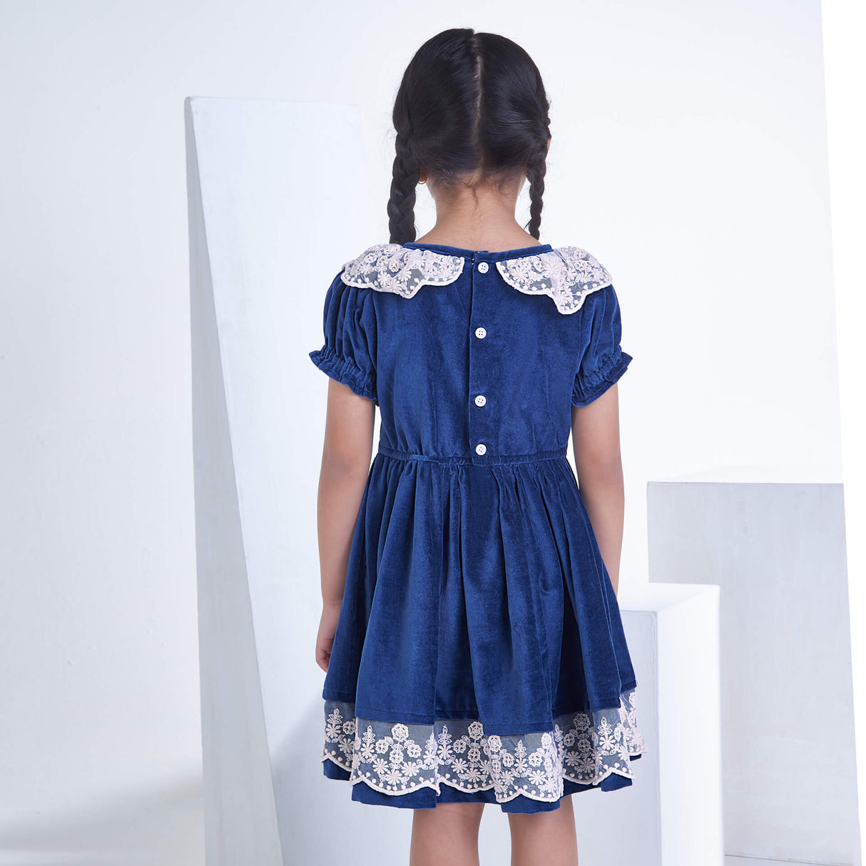 A Girl seen from behind wearing Navy velvet dress ,fastened by buttons