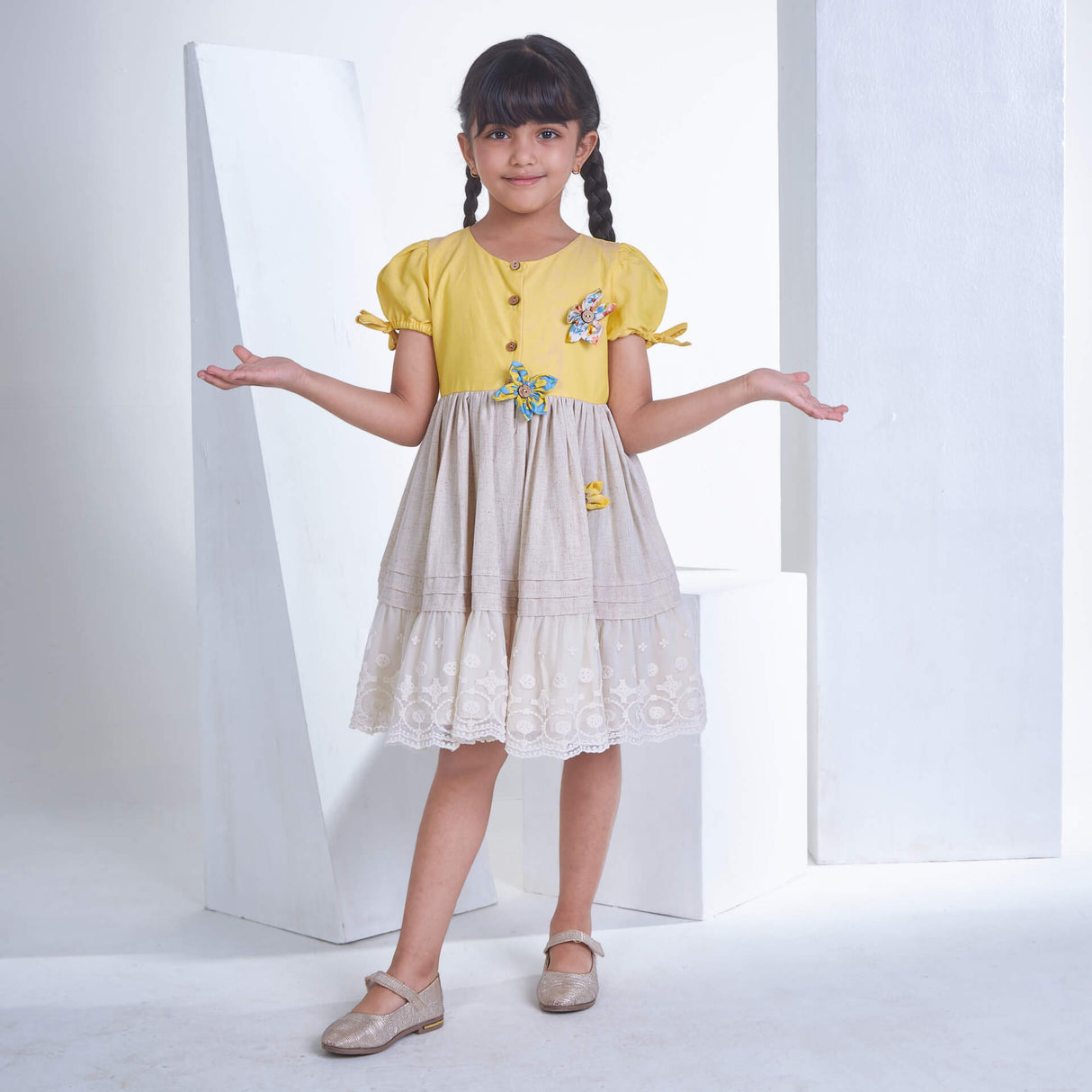 A girl dresses in yellow flower applique dress adorned with lace