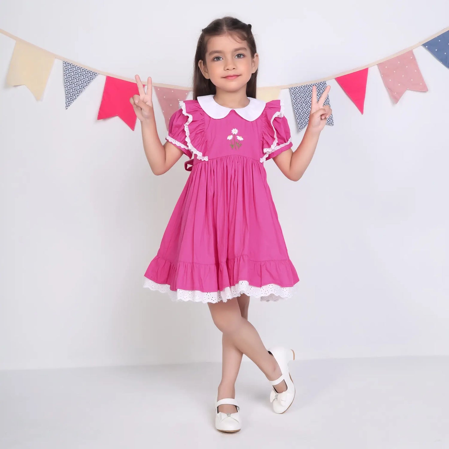 A little girl dressed in a pink embroidered cotton puffed sleeves dress.