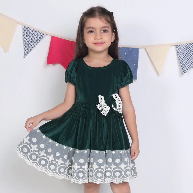 A girl dressed in a green ivory lace velvet puffed sleeves dress.