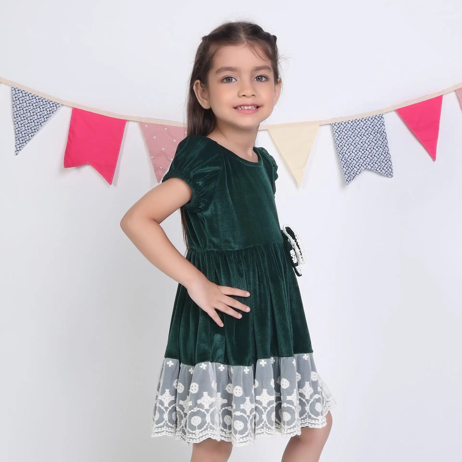 Side view of a girl in a green ivory lace velvet puffed sleeves dress.