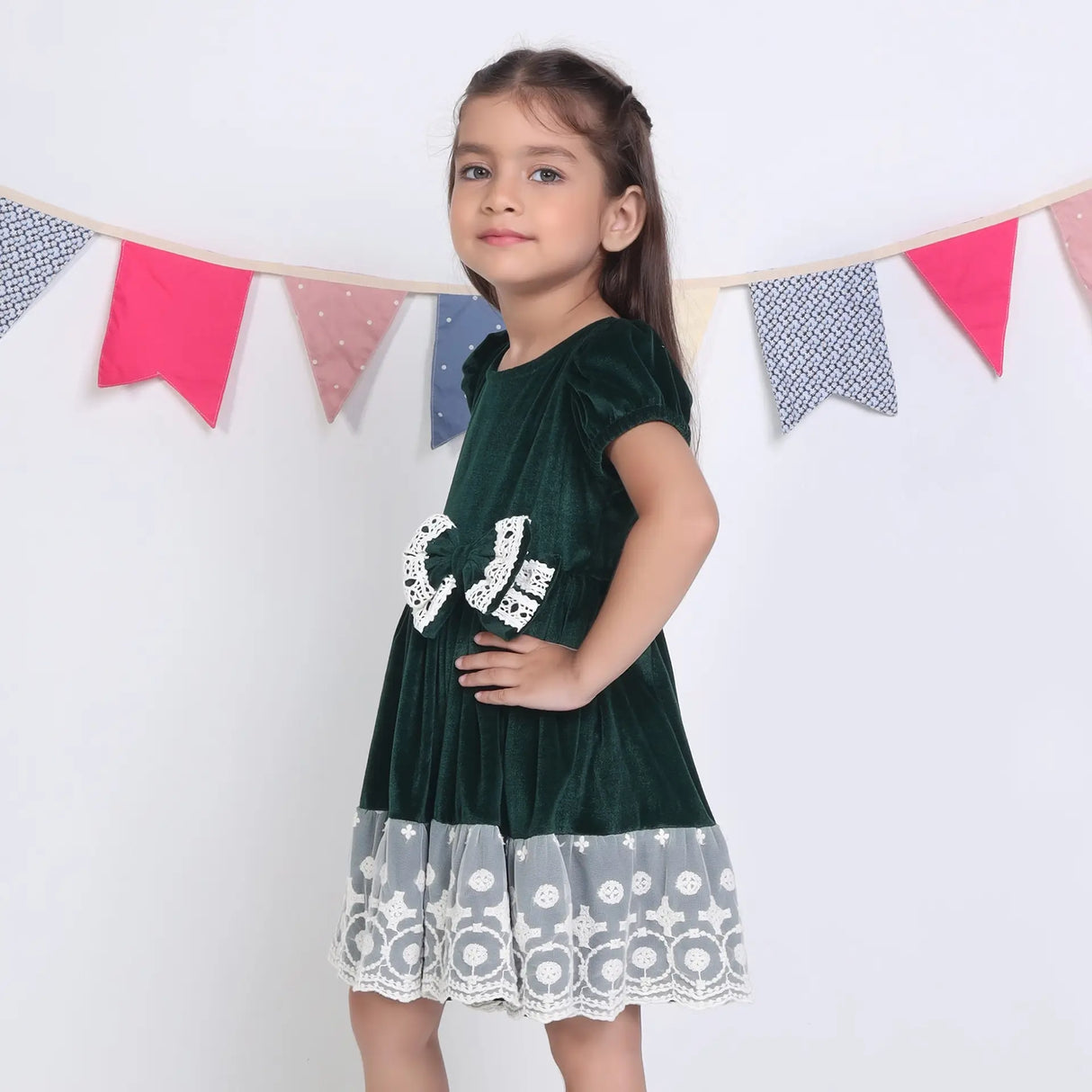 Side view of a girl in a green ivory lace velvet puffed sleeves dress.