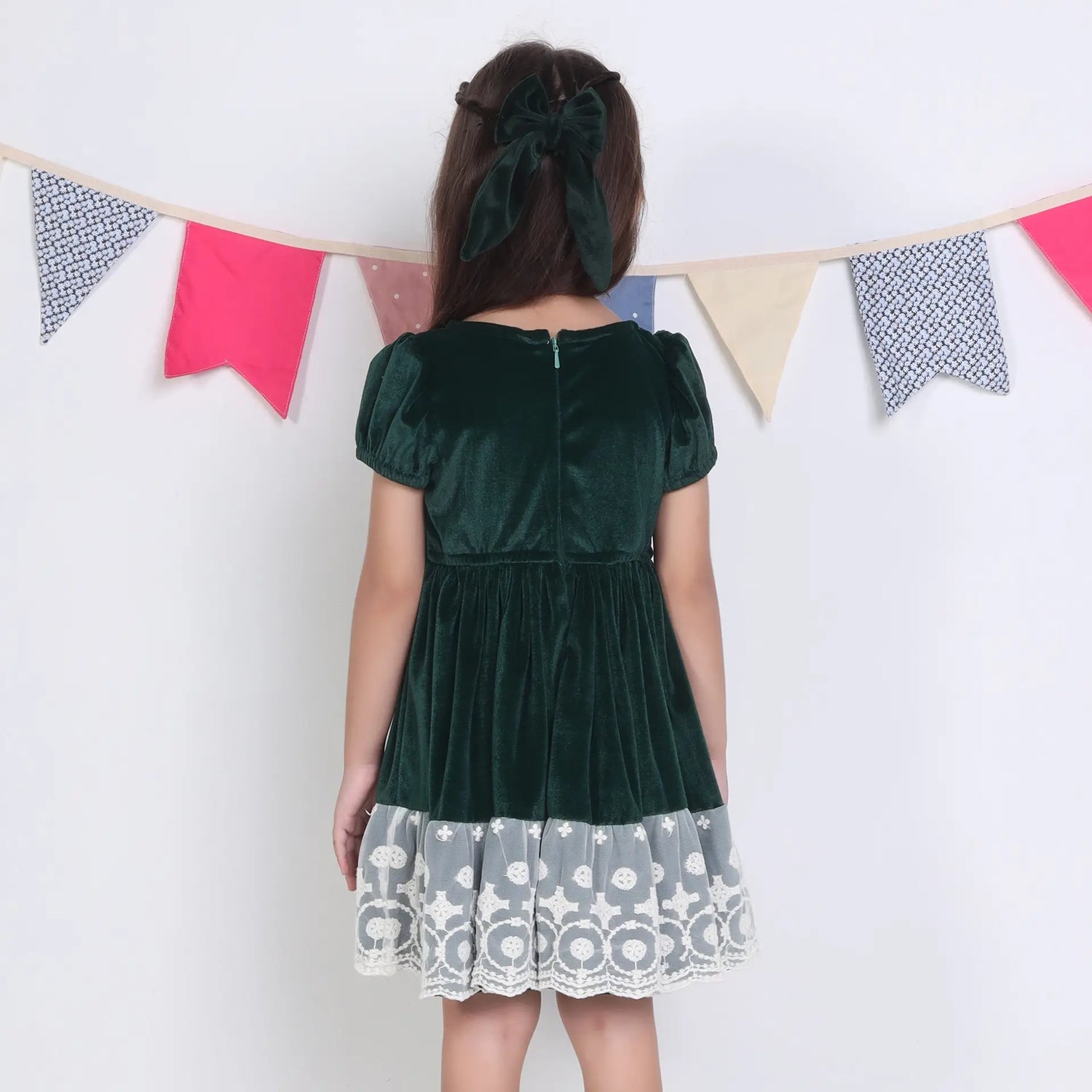 Back view of a girl in a green ivory lace velvet puffed sleeves dress.