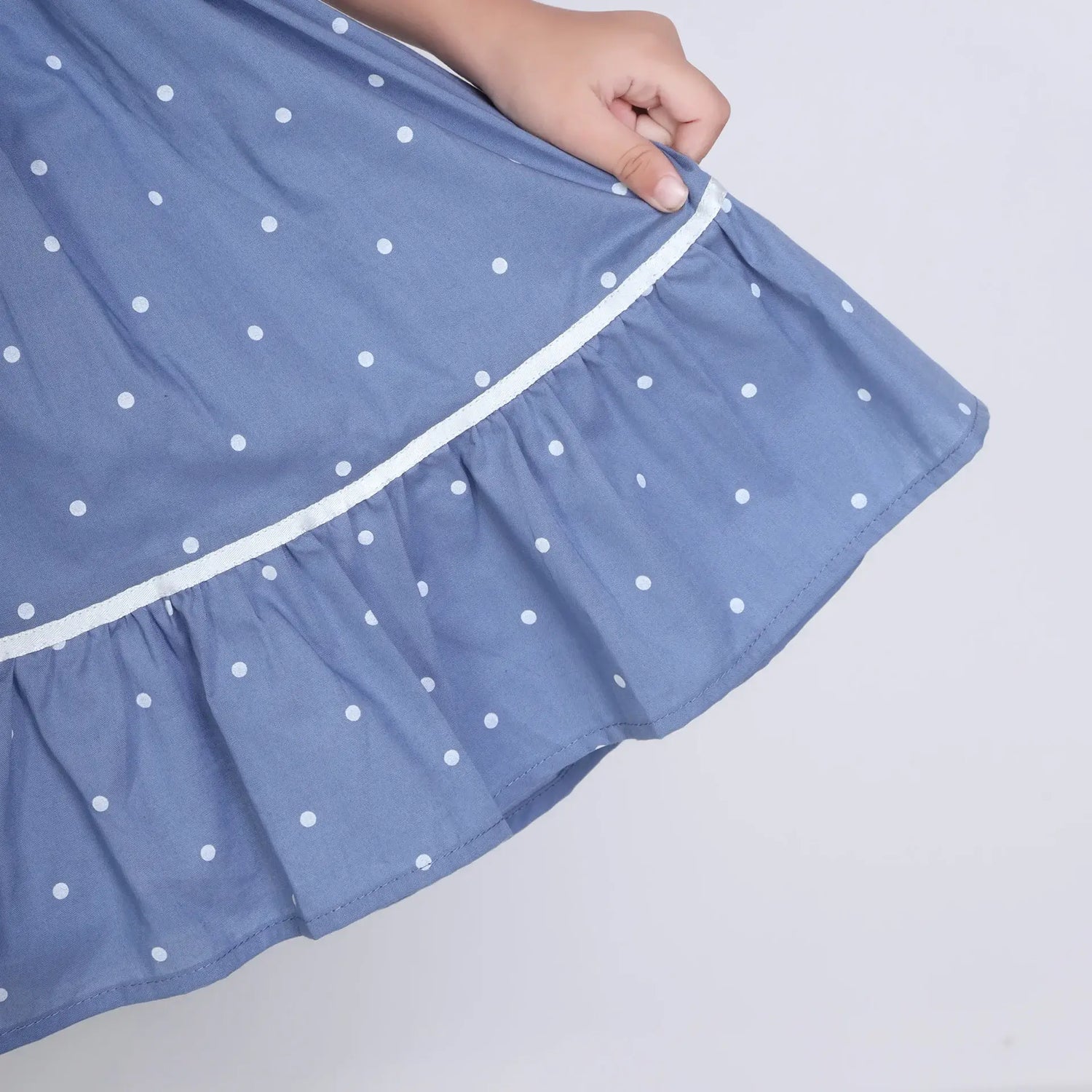 "Close-up of the skirt of a blue embroidered cotton dot printed dress."