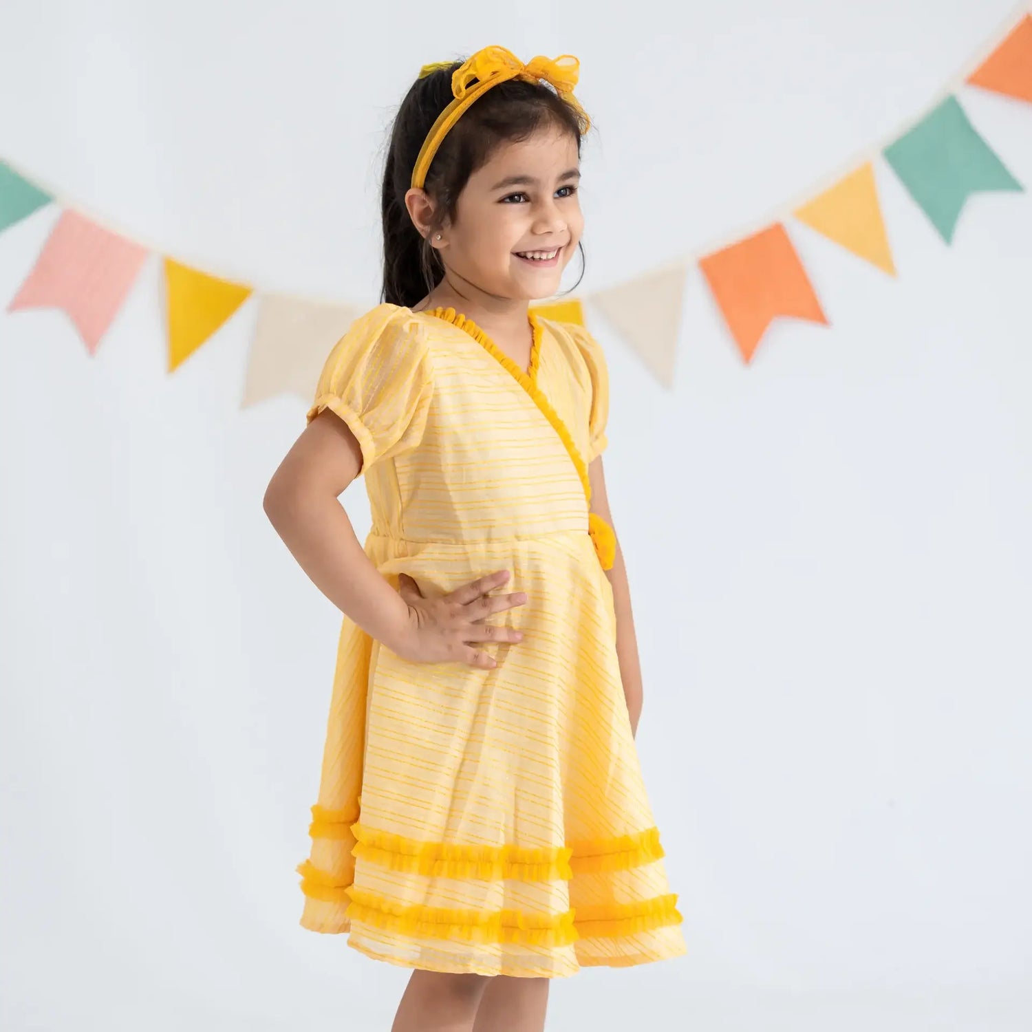 "With her hand on her hip, a girl dressed in a yellow crossover chanderi puffed sleeves dress."