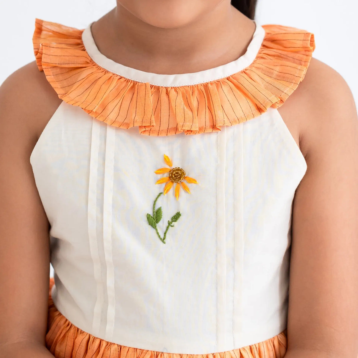 Close-up of the ruffle neckline and hand embroidery on the orange hand embroidered zari striped chanderi sleeveless dress.