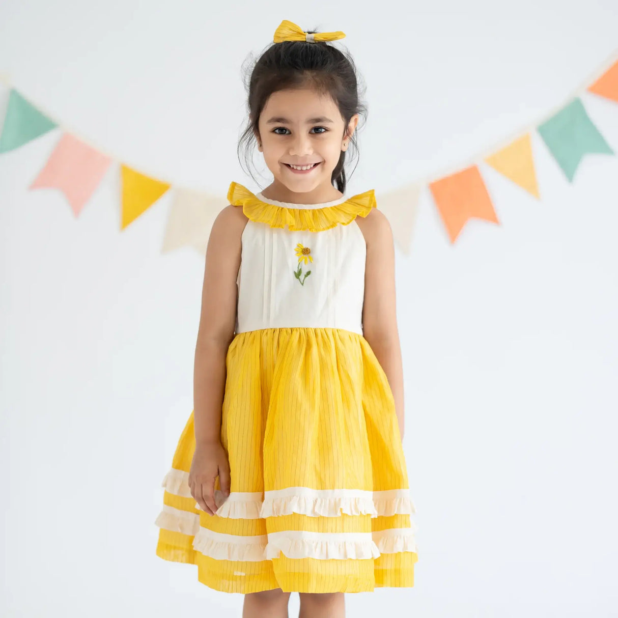 "A girl dressed in a yellow hand embroidered zari striped chanderi sleeveless dress."