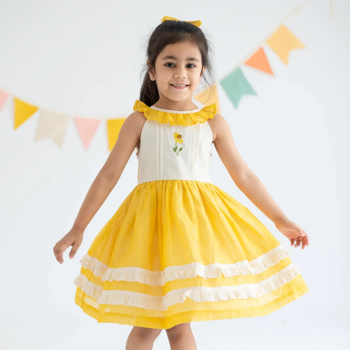 "A girl twirling in a yellow hand embroidered zari striped chanderi sleeveless dress."