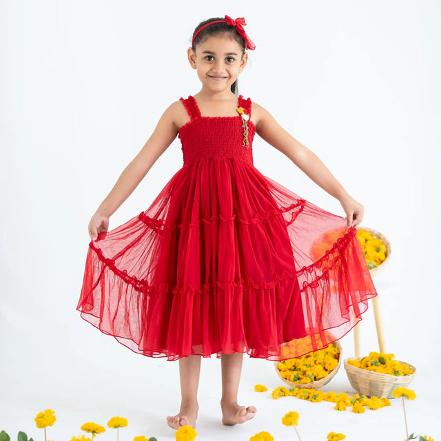 A girl playfully stretches the skirt of a red hand-embroidered crochet nylon tulle sleeveless dress.