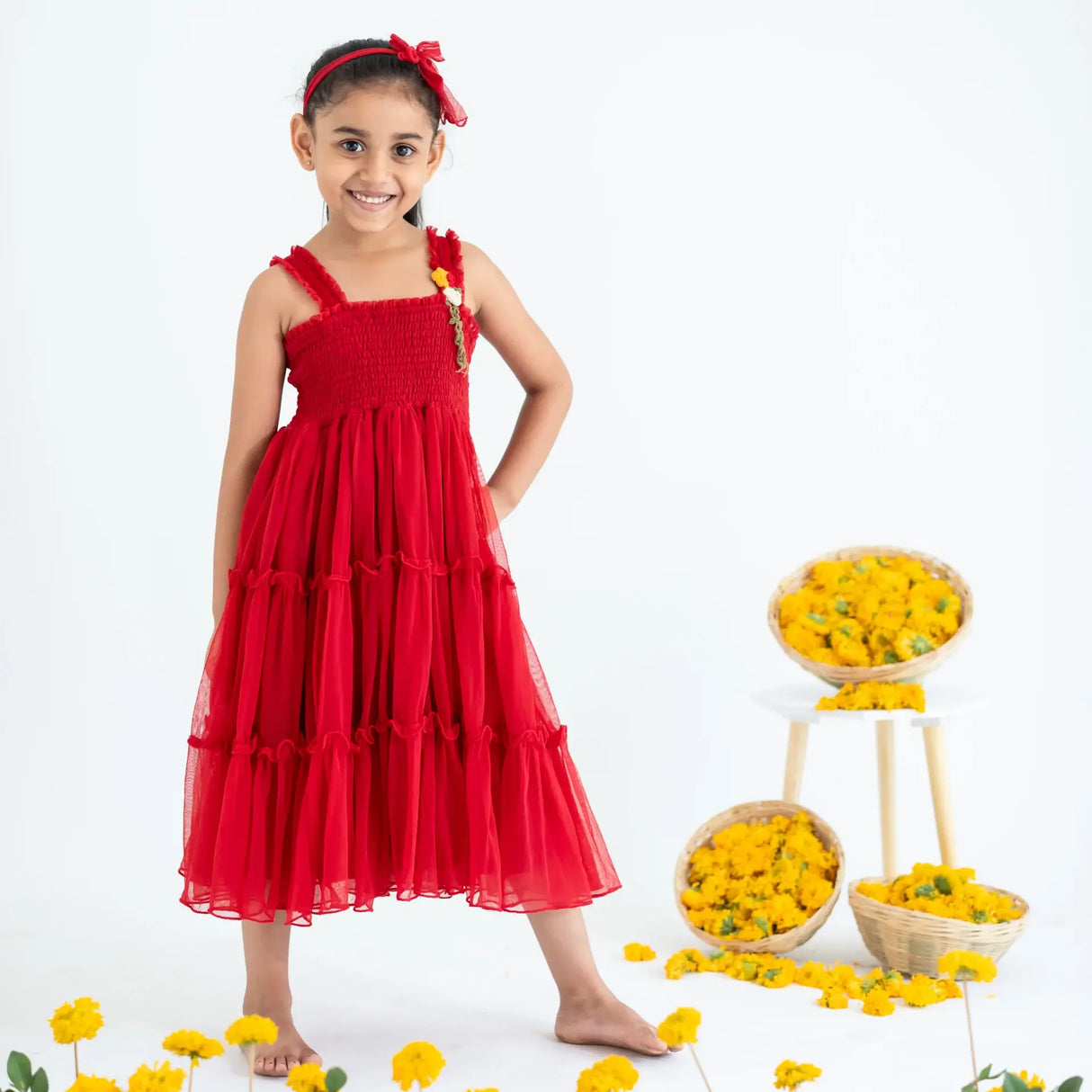 A little girl stands with one hand on her hip, wearing a red hand-embroidered crochet nylon tulle sleeveless dress.