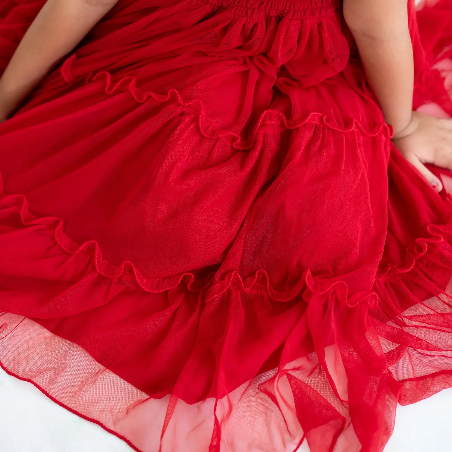 Close-up of the ruffles on a red hand-embroidered crochet nylon tulle sleeveless dress.