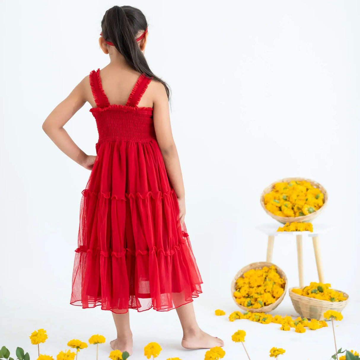 A girl seen from behind, wearing a red hand-embroidered crochet nylon tulle sleeveless dress.