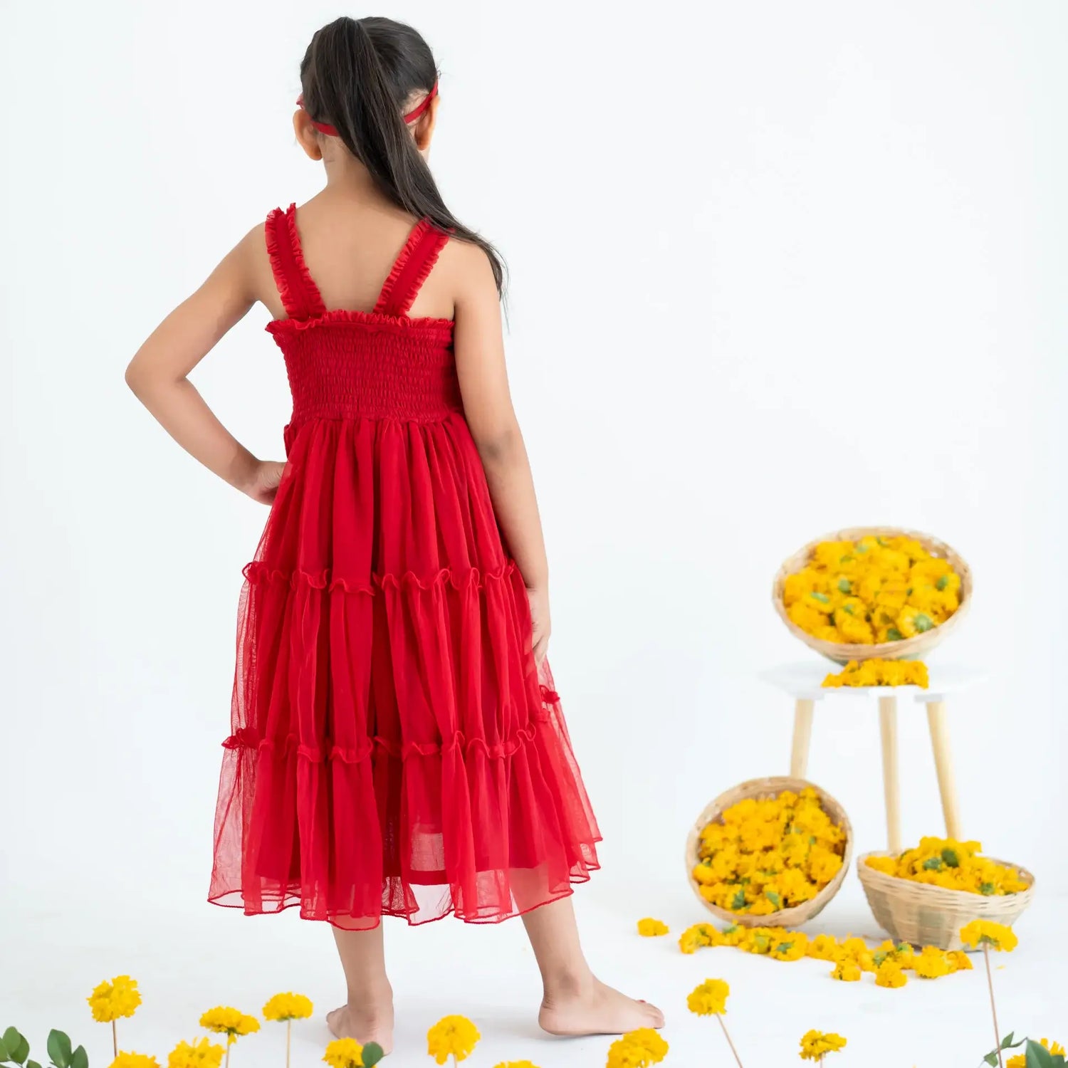 A girl seen from behind, wearing a red hand-embroidered crochet nylon tulle sleeveless dress.