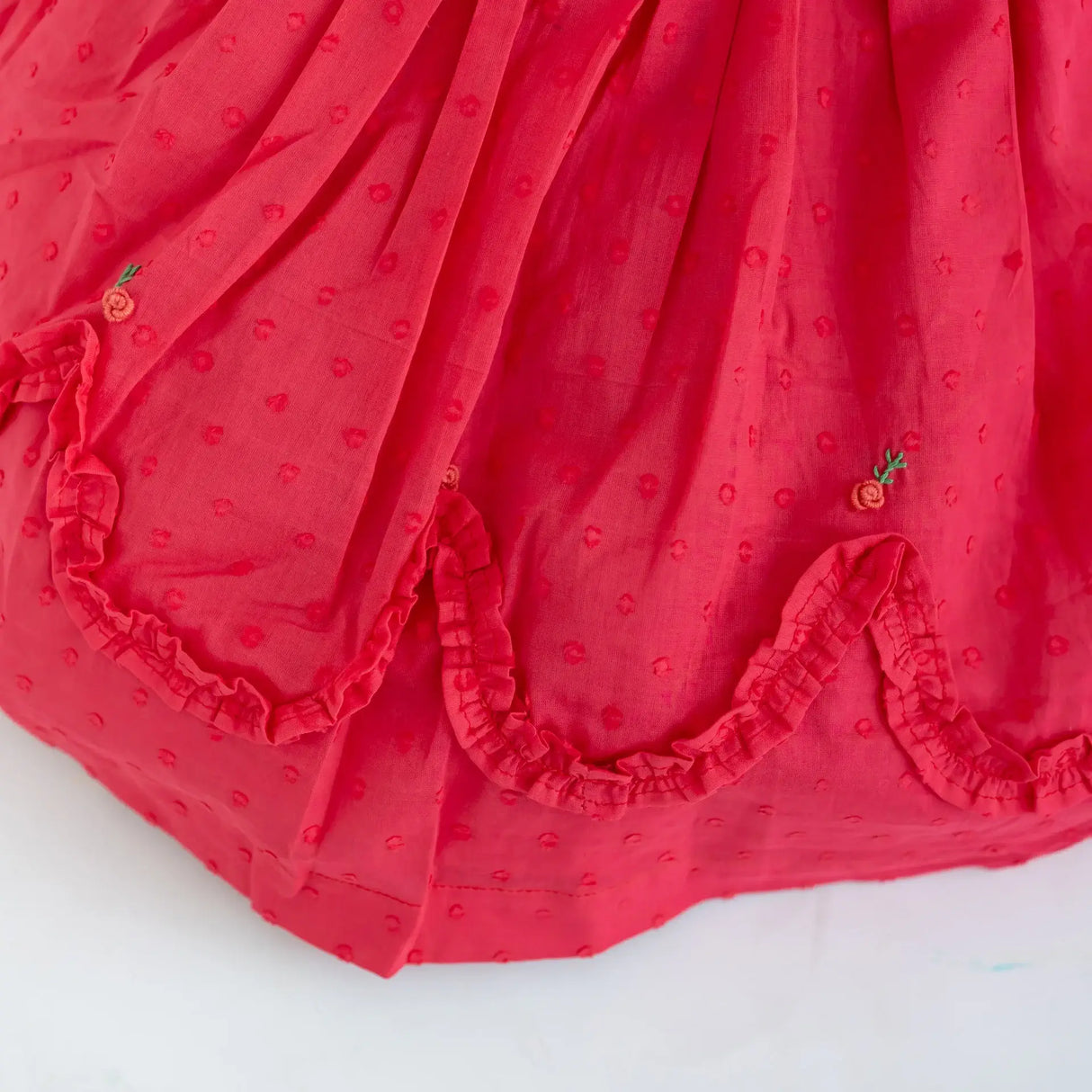 "Close-up of the scallop ruffles on the coral swissdot hand smocked and embroidered cotton puffed sleeves dress."