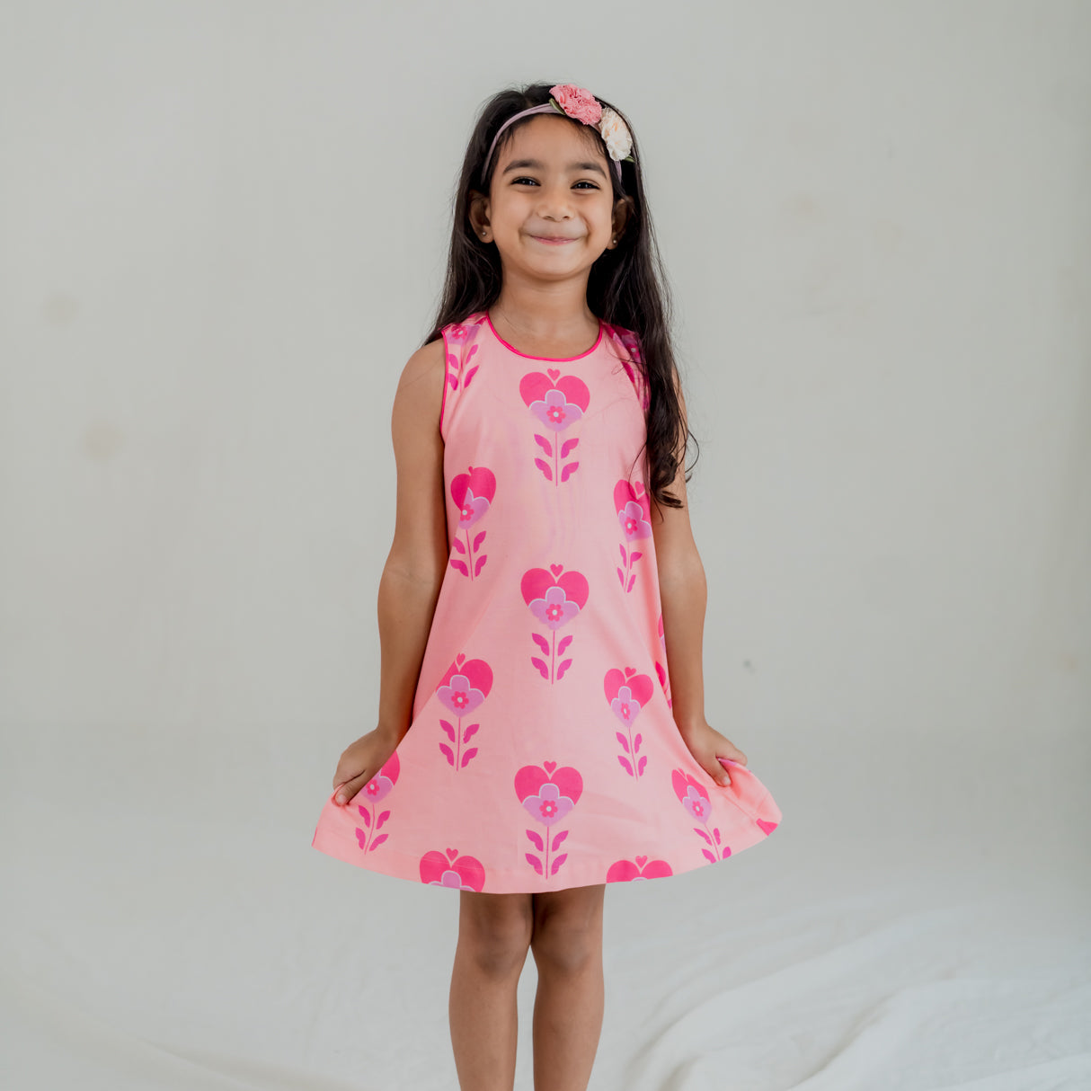 a little girl dressed in pink heart print a line dress