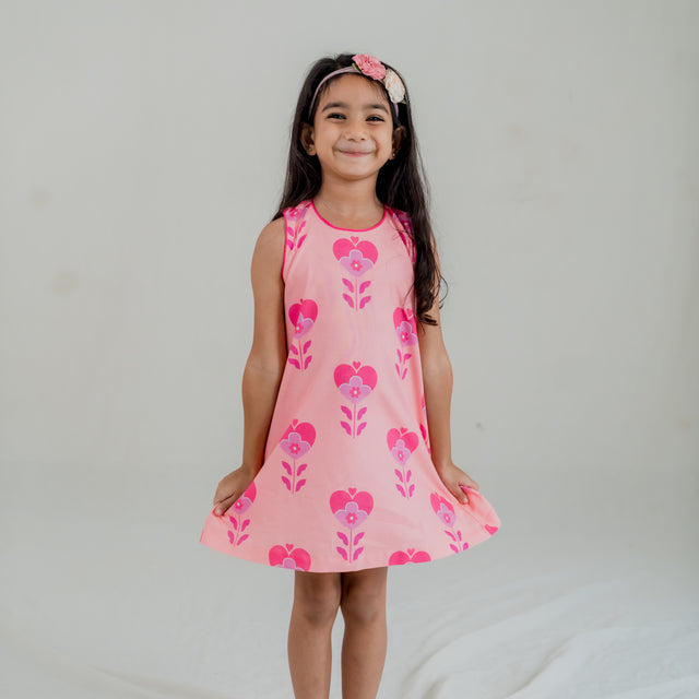 a little girl dressed in pink heart print a line dress