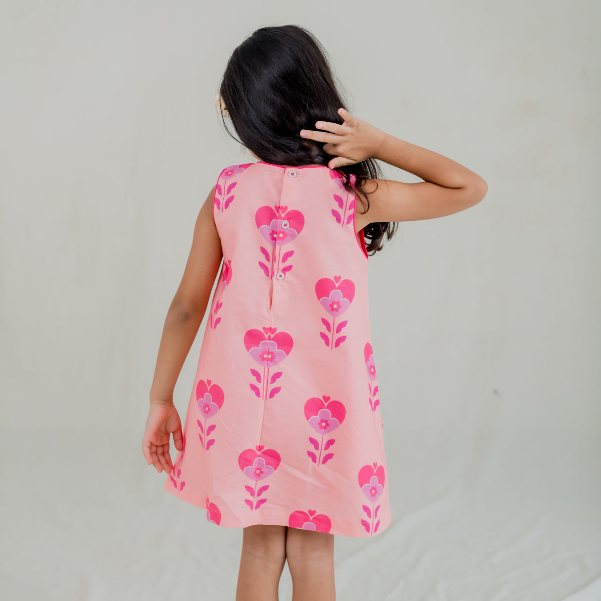 back view of little girl dressed in pink heart print a line dress
