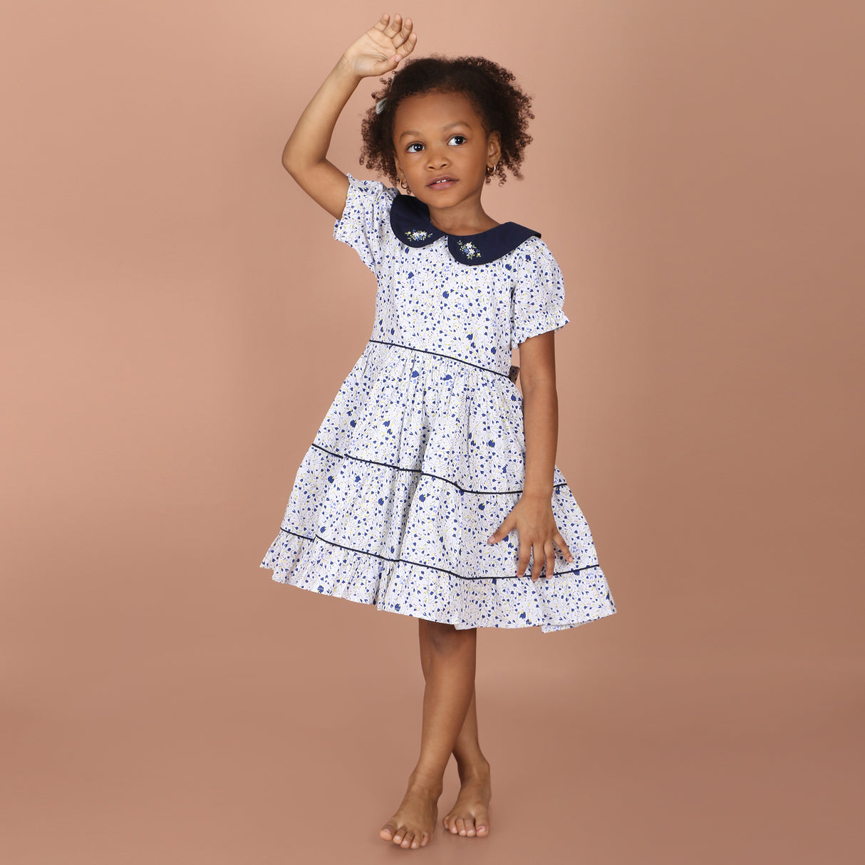 full view of white floral hand-embroidered layered girls dress with navy collar