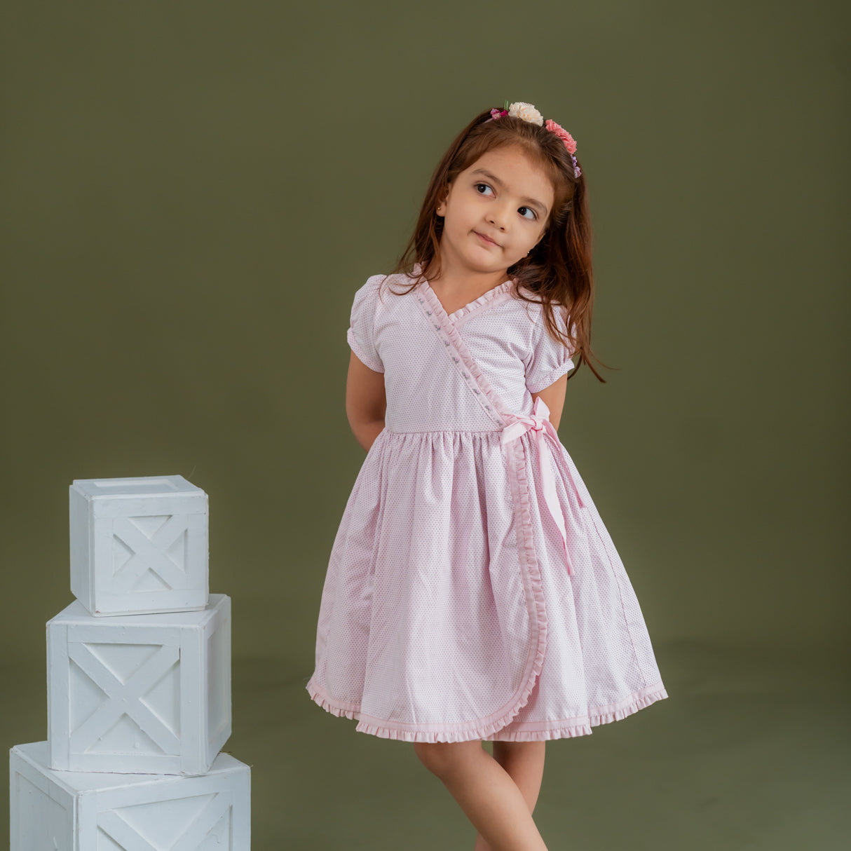 a little girl dressed in pink crossover dress