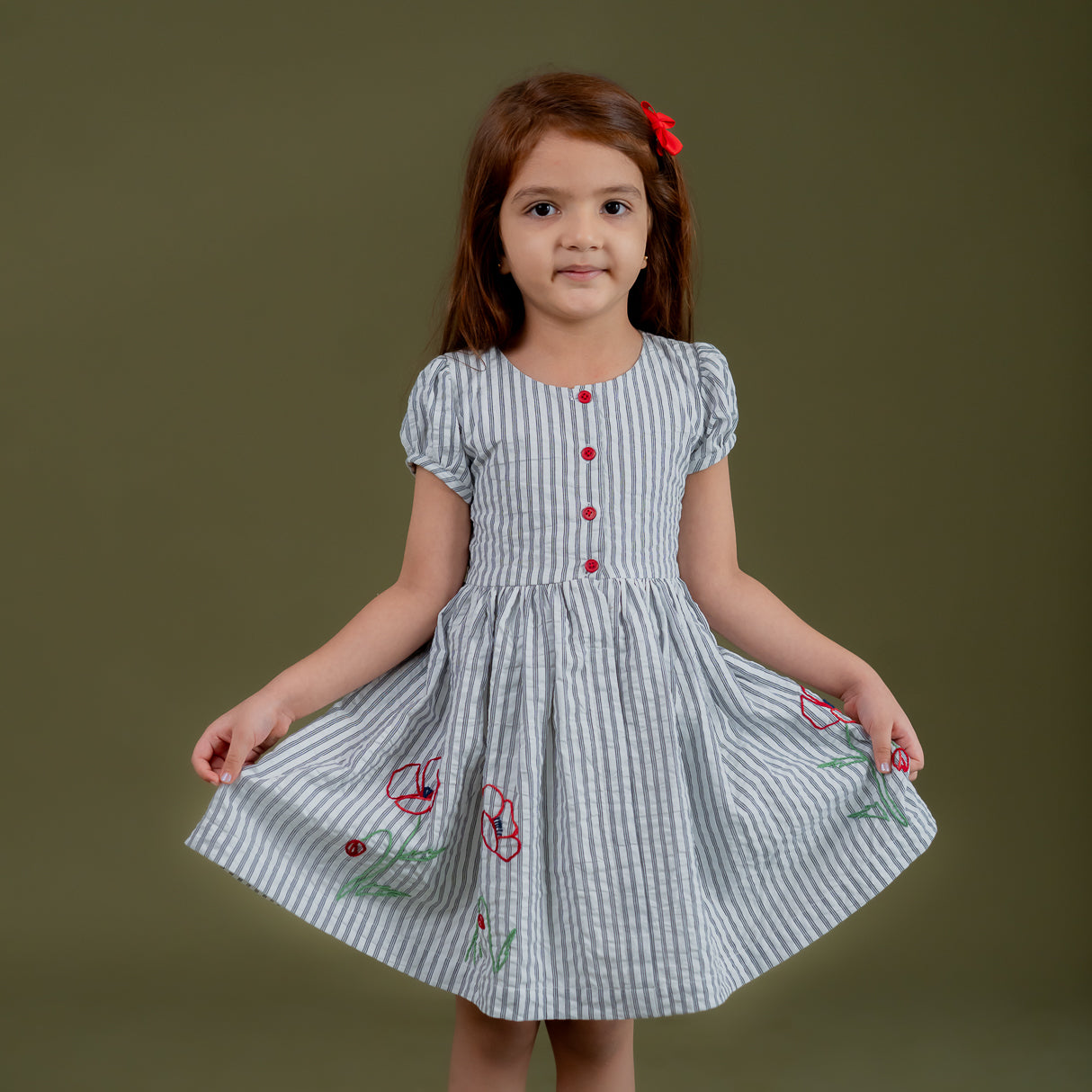 a little girl dressed in blue striped dress with floral embroidery