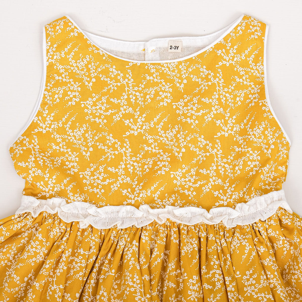 close-up of neckline piping and ruffle waist detail