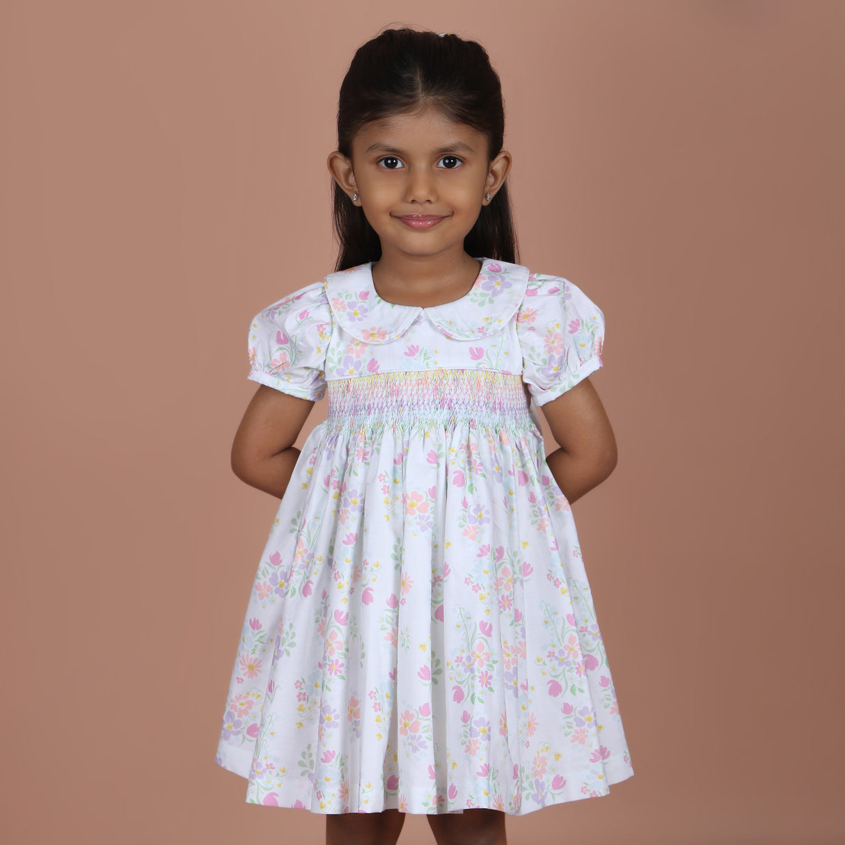 girl wearing white floral dress with rainbow smocking