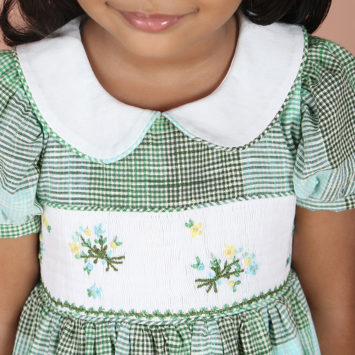 Detailed collar and bodice view of green check girls dress with floral embroidery