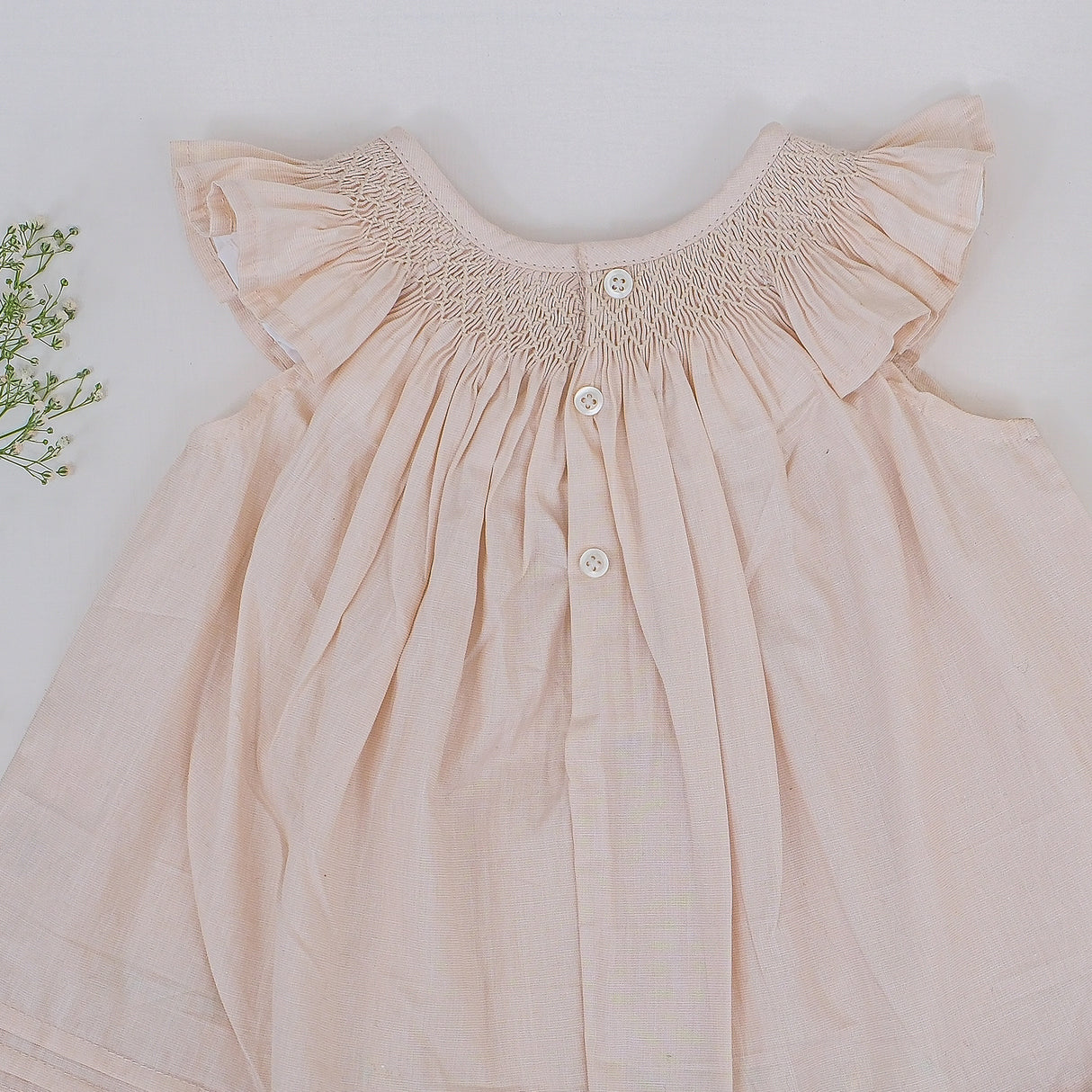 Back view of tan smocked dress with button closure