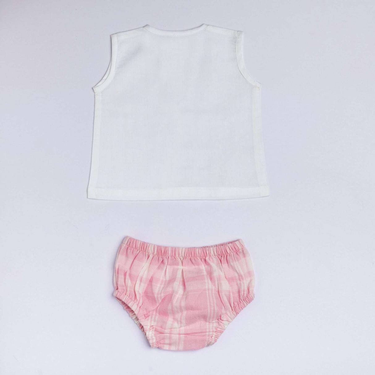 Flatlay of jabla with hand embroidered flower and bee with pin tuck detail and pink plaid bloomers