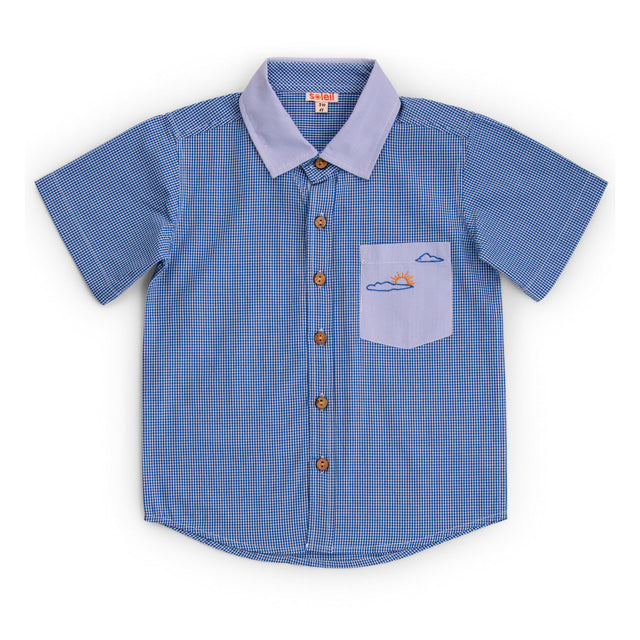 Flatlay of shirt with two closely coordinated fabrics in royal blue with signature sun themed embroidery on pocket