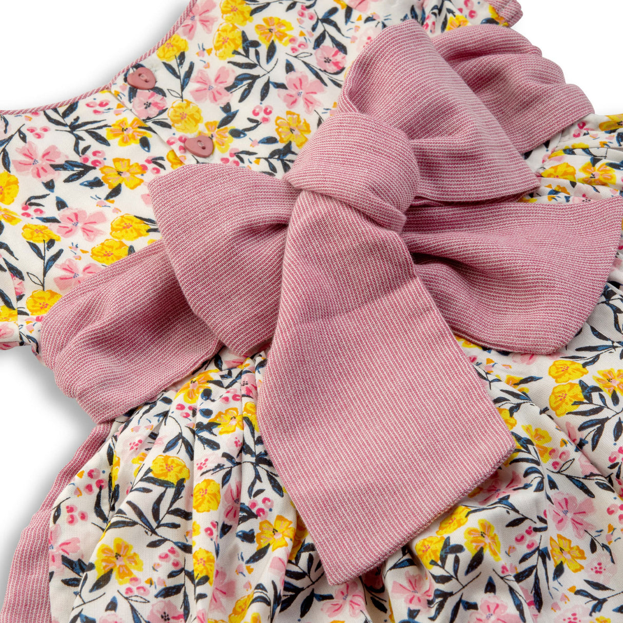 Large decorative bow in dusty pink over an ivory print dress