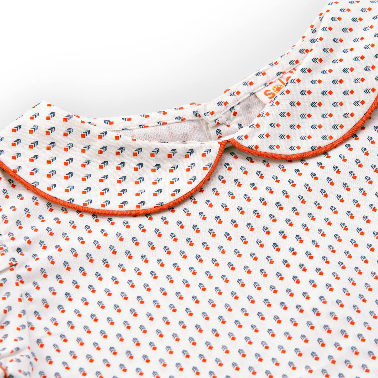 Close up of printed blouse with gathered sleeves and back button fastening with orange piping