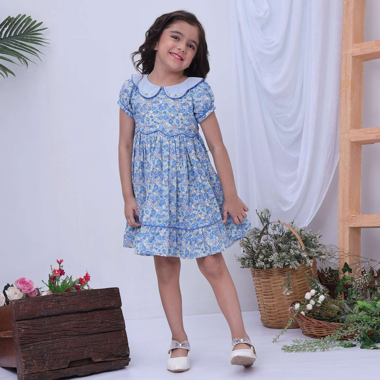 Girl in a blue floral print scallop waistline dress with hand embroidered collar