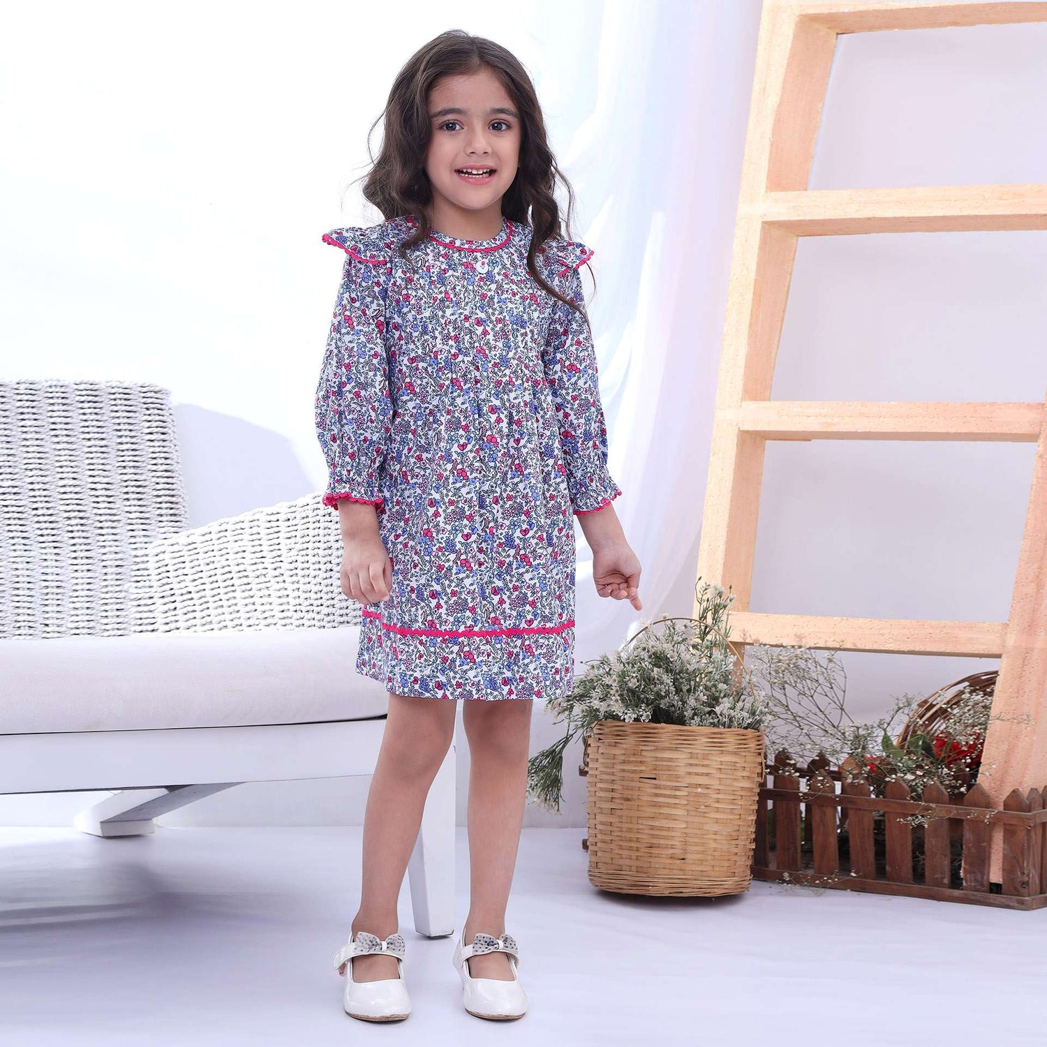 A little girl in floral full sleeve dress with ruffled hems and gathered sleeves with ruffles on shoulder and neckline