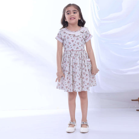 A little girl in blue fil-à-fil floral printed dress with boat neck, three-stack sleeves and delicate embroidered tulle