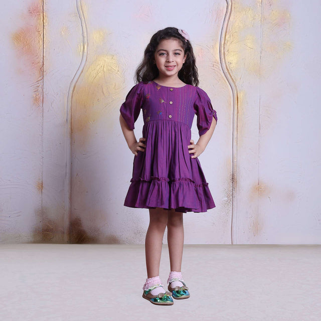 A young girl in berry pink cotton dress with beautiful bead work, hand embroidery and wooden buttons