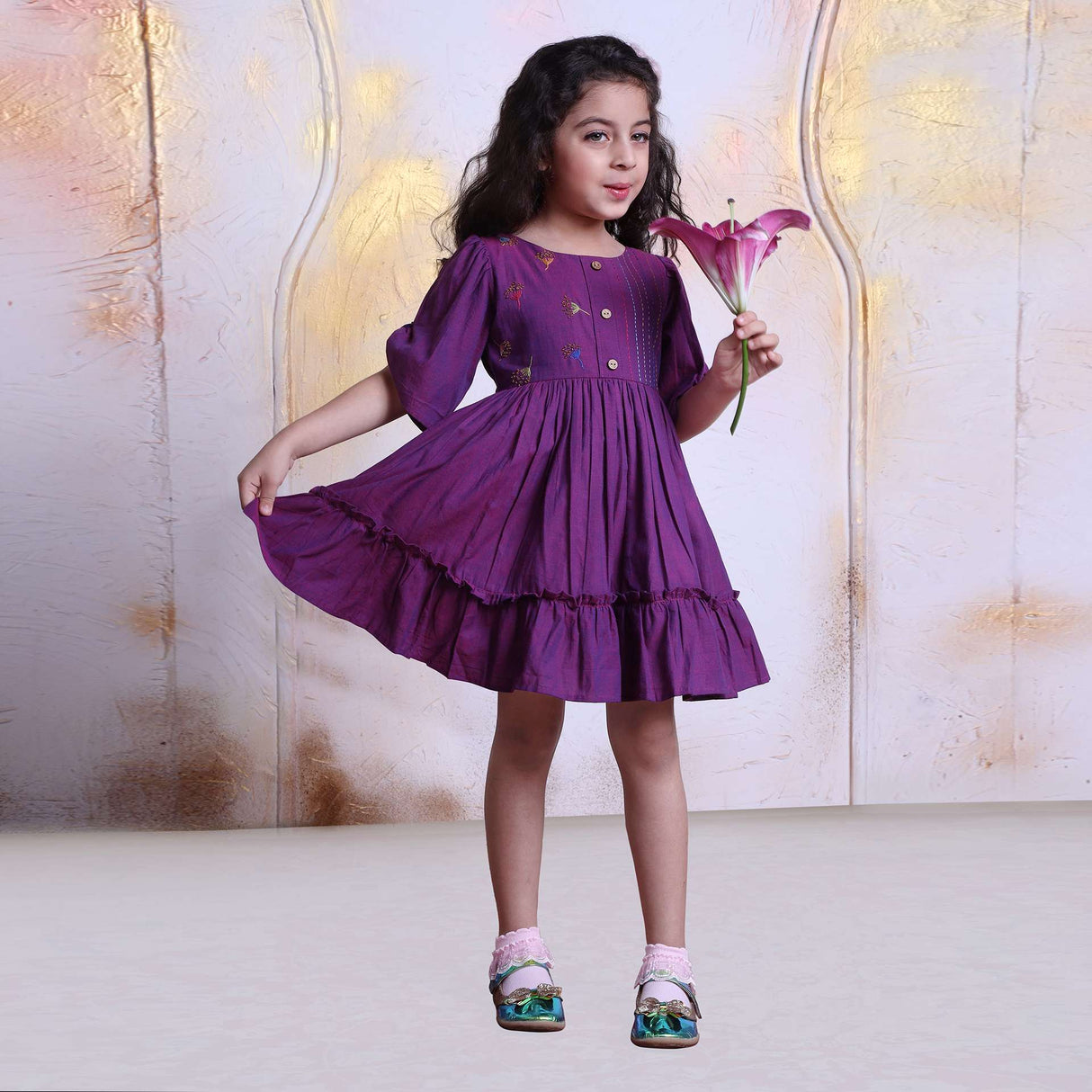 A young girl in berry pink cotton dress with beautiful bead work, hand embroidery and wooden buttons