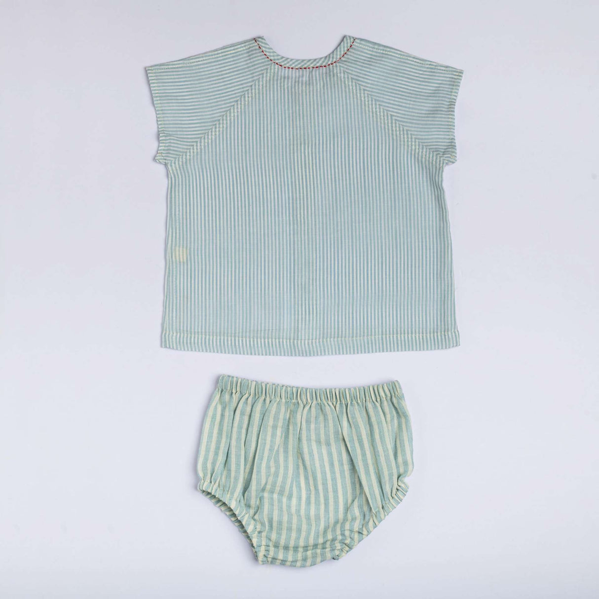 Flatlay of green hand embroidered raglan sleeve jabla and bloomers set