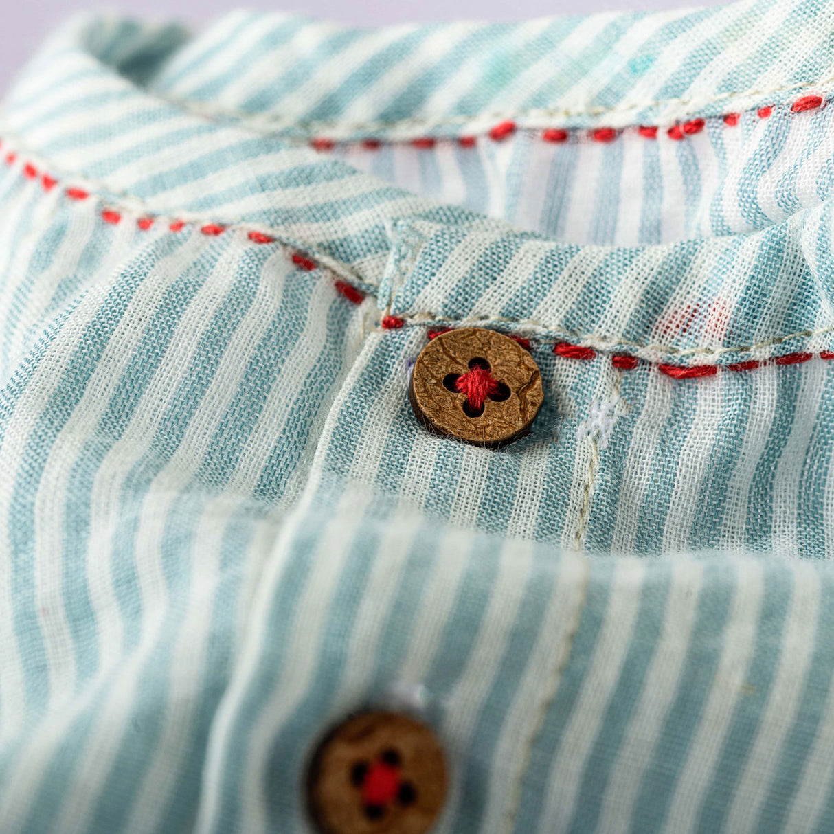 Close-up of red kantha hand embroidered details on sage green striped raglan sleeve jabla