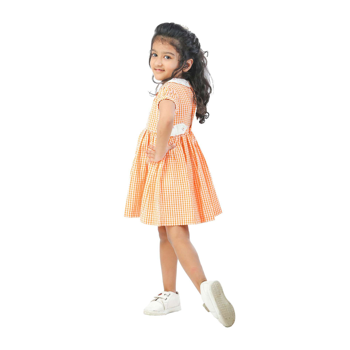 Side view of a youg girl wearing an orange gingham dress