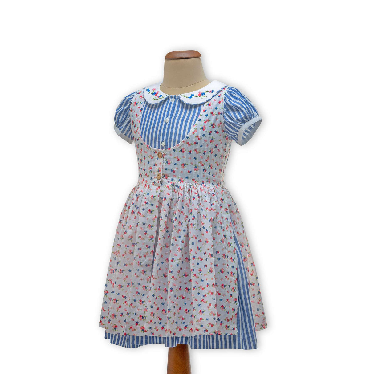 Striped blue dress on a mannequin, with a hand embroidered collar and a floral printed overdress