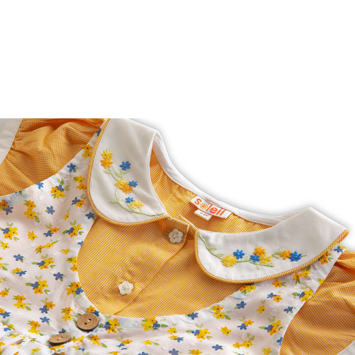 Close up of floral overdress with side slits and back ties over orange gingham dress