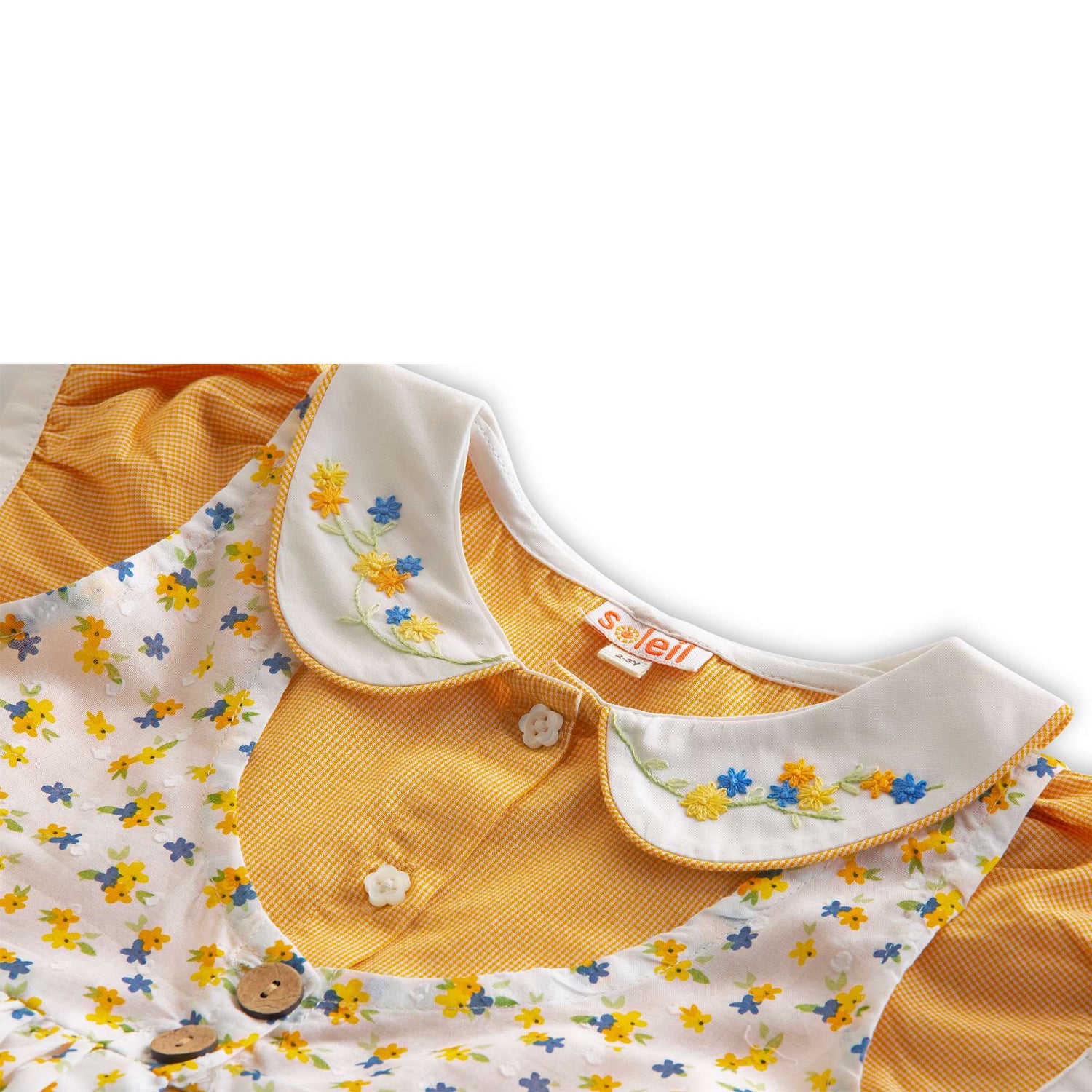 Close up of floral overdress with side slits and back ties over orange gingham dress