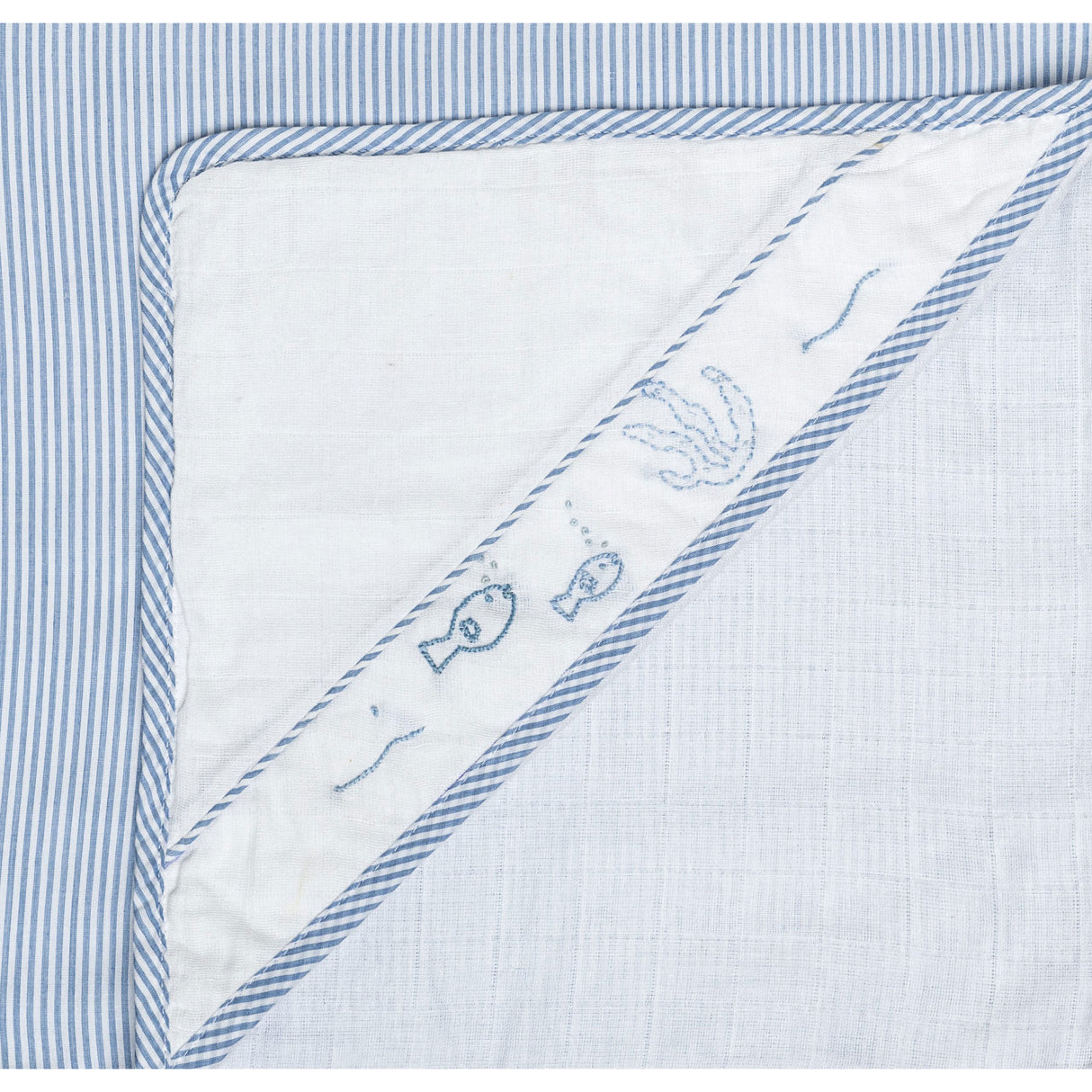 Close up of baby blue infant head wrap with hand embroidered motif in corner flap and contrast piping along edges