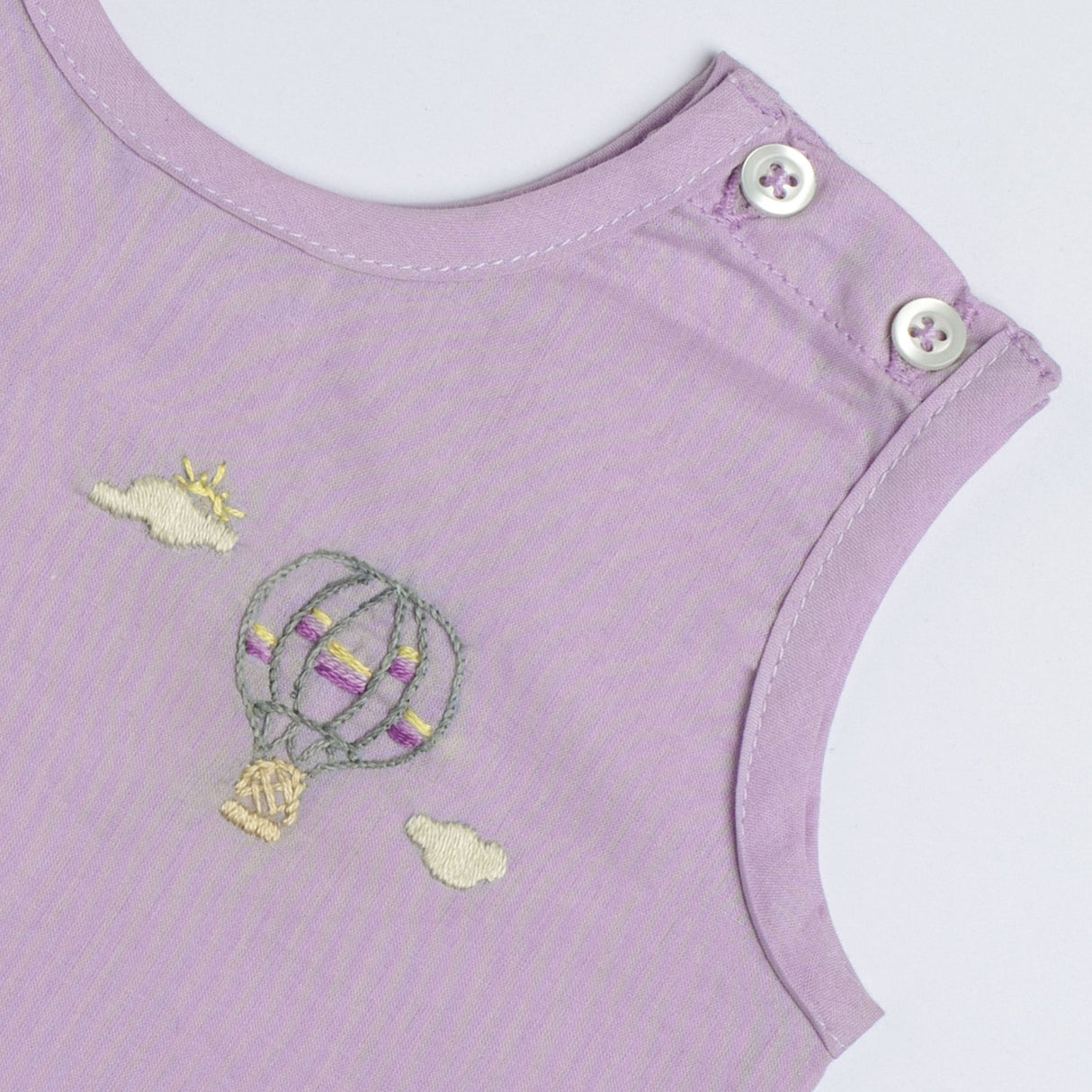 Hand embroidered hot air balloon floating between clouds on a lavender voile