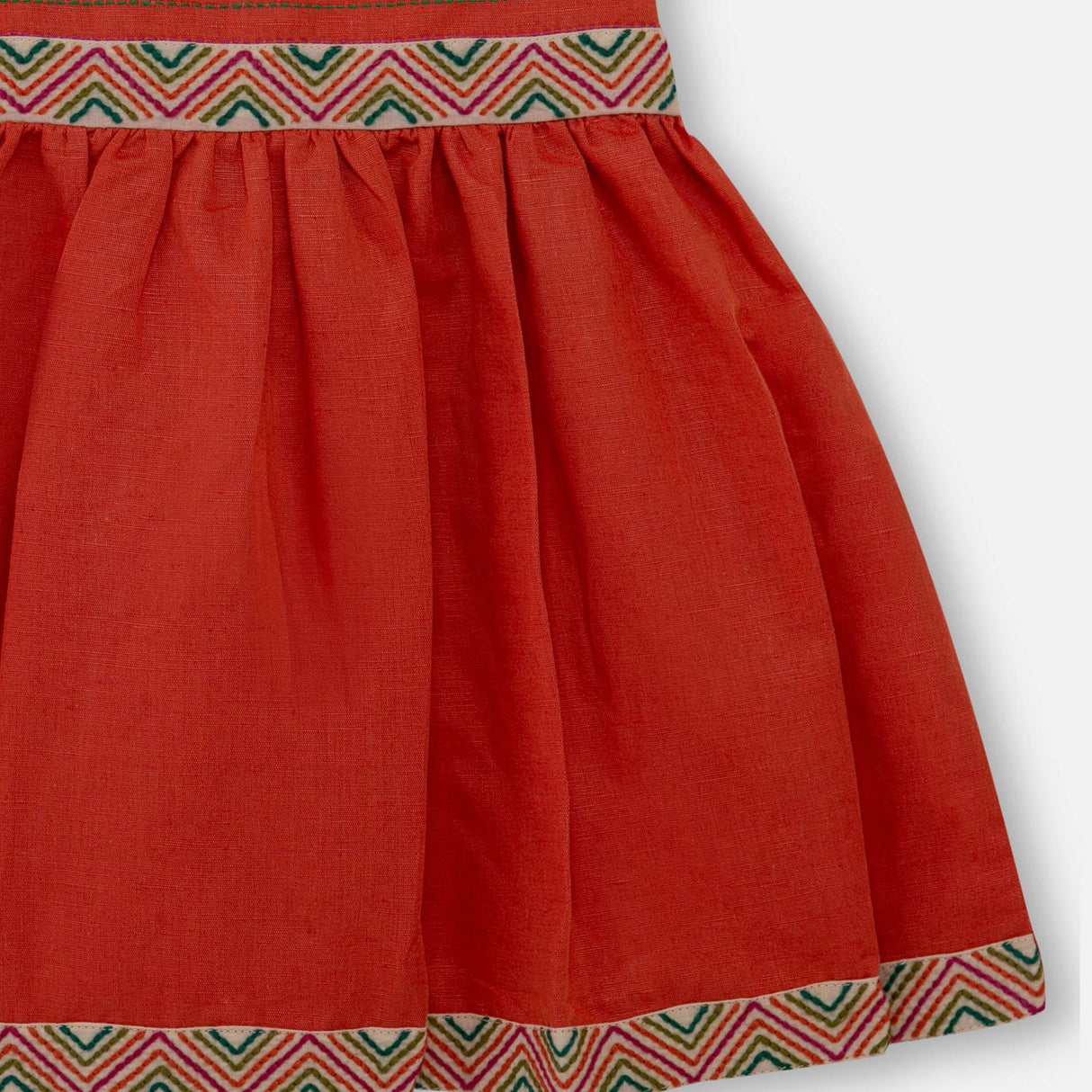 Close-up of burnt-orange linen dress with colourful embroidered waistline with a Kantha-work hand-embroidered bodice