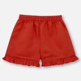 Flatlay of burnt-orange linen shorts that are paired with matching dress with colourful embroidered details