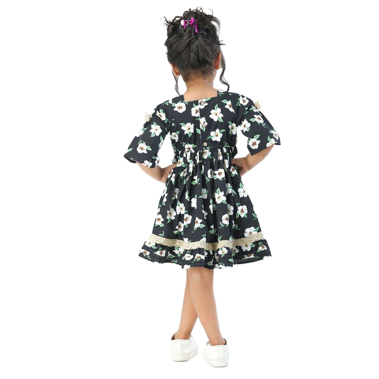 Girl stands with her back to camera wearing a black, white and green floral print casual dress