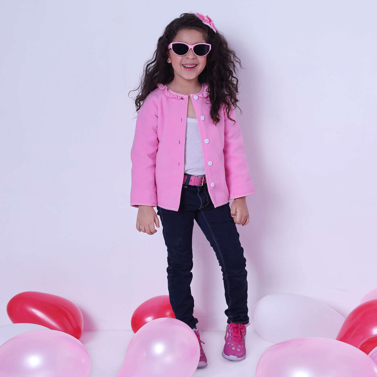 A little girl wearing fleece jacket lined in soft pink cotton, with pink gingham edging and a neckline ruffle
